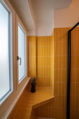 a bathroom with a shower with yellow tile at Vintage Cipro Apartment in Rome