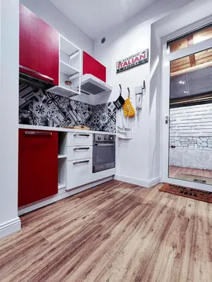a kitchen with red and white cabinets and wood floors at Moderno appartamento Cornelia-San Pietro con Giardino in Rome