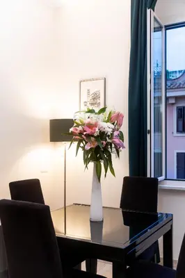 a vase of flowers on a glass table with chairs at C&Y Apartments - Roma Vaticano St Peter - Luxe Penthouse Flat in Rome