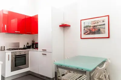 a kitchen with red cabinets and a table in it at C&Y Apartments - Roma Vaticano St Peter - Luxe Penthouse Flat in Rome