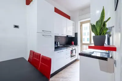 a white kitchen with red accents and a plant at Colosseo Roma color's in Rome