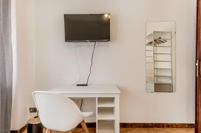 a white desk with a white chair and a tv on a wall at MARCONI31Eredia in Rome