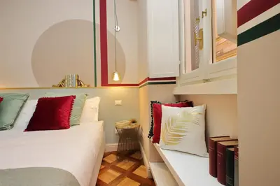 a small room with a bed with red and white pillows at YCH-Bright Suite Navona in Rome