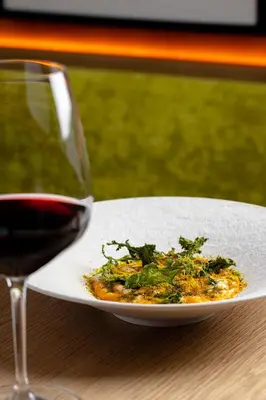 a plate of food next to a glass of wine at The Rome EDITION in Rome