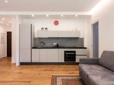 a kitchen with white cabinets and a couch in a living room at Majo Suite in Rome