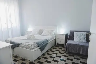 a white bedroom with a bed and a chair at La Casa di Klaudia in Rome