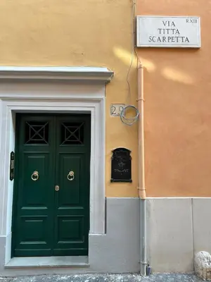 a green door next to a building with a sign at Garden House Trastevere in Rome