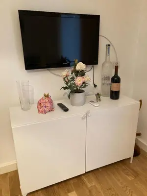 a white cabinet with a tv and a bottle of wine at FAIROME Apartment Farnesina in Rome