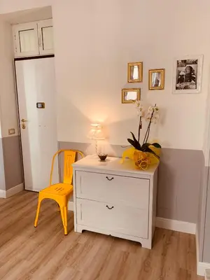 a room with a white dresser and a yellow chair at A casa di Clara in Rome