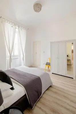 a white bedroom with a large bed and a desk at A casa di Clara in Rome
