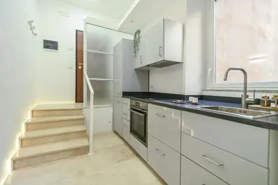 a kitchen with white cabinets and a sink and stairs at Suite 109 in Rome
