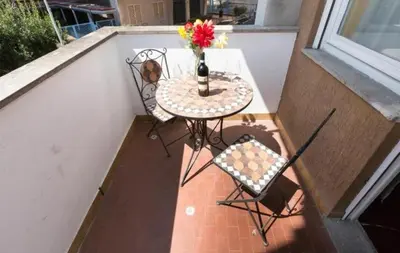 a table and chairs on a balcony with a vase of flowers at Nice Apartment with Balcon in Rome