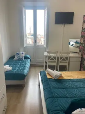 a room with two beds and a couch and a table at Casa di Mochi in Rome