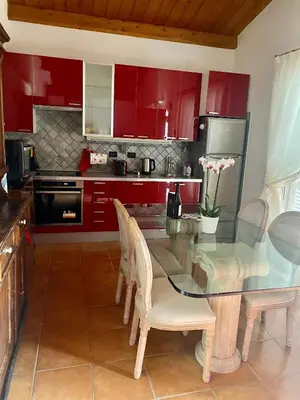 a kitchen with red cabinets and a glass table and chairs at Villette Aldobrandeschi Urban Oasis Vacation Homes in Rome