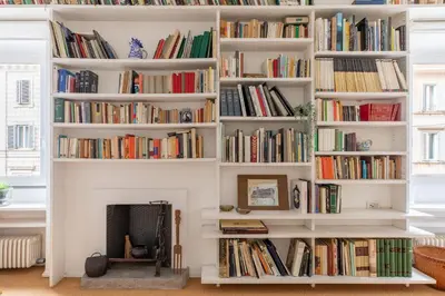 a book shelf filled with books next to a fireplace at iFlat The Carpet Apartment in Rome