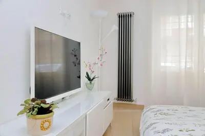 a white bedroom with a flat screen tv on a dresser at Casina degli Eroi in Rome