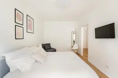 a white bedroom with a large bed and a flat screen tv at Trastevere Boutique Apartment in Rome