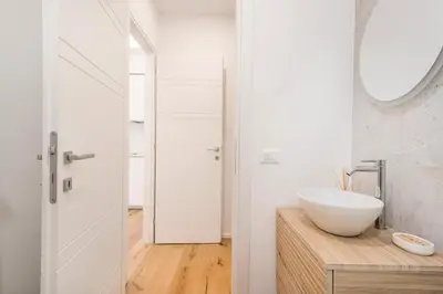 a white bathroom with a sink and a mirror at Trastevere Boutique Apartment in Rome