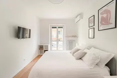 a white bedroom with a large bed with white sheets and pillows at Trastevere Boutique Apartment in Rome