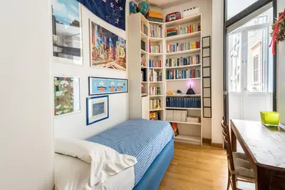a bedroom with a bed and a desk and bookshelves at Maison Regola, Styilish Apt in Campo De Fiori in Rome