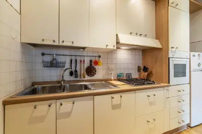 a kitchen with white cabinets and a stainless steel sink at GuestHost - Sunny Apartment Piramide in Rome