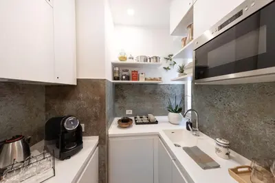 a small kitchen with white cabinets and a sink at Barcaccia Exclusive apartment in Rome