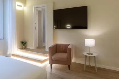 a bedroom with a chair and a television on the wall at Elegantia Luxury Rooms in Rome