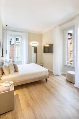 a bedroom with a large bed and two windows at Elegantia Luxury Rooms in Rome
