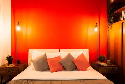 a bedroom with a red wall with a bed with pillows at Appartamento via di San Martino ai Monti in Rome