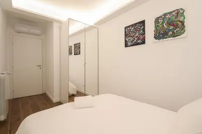 a white bedroom with a bed and a mirror at Ziani 5 Rome Vatican Apartment in Rome