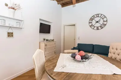 a living room with a table and a clock on the wall at Navona Atmosphere A few meters from Piazza Navona !! in Rome