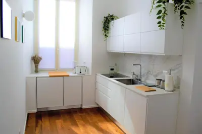 a white kitchen with white cabinets and a sink at Eternal City Apartment in Rome