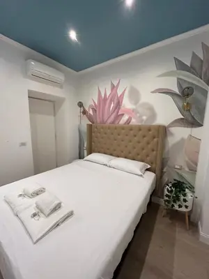 a bedroom with a white bed with a painting on the wall at Raffaello's Place in Rome