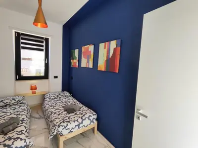 a bedroom with two beds and a blue wall at Il quattro e l'otto in Rome