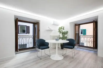 a white table and chairs in a room with windows at My Piazza Navona Jacuzzi Suite - Top Collection in Rome
