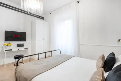 a white bedroom with a bed and a tv at White flat Ground Floor in Rome