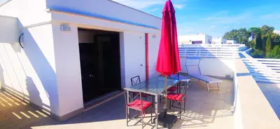 a balcony with a table and chairs and a red umbrella at Cosy penthouse loft with stunning view in Rome