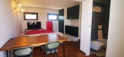 a living room with a table and a room with a bed at Cosy penthouse loft with stunning view in Rome