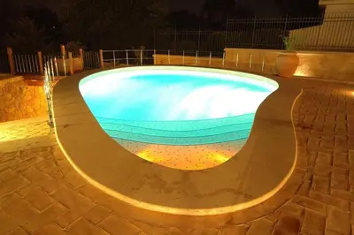 a large swimming pool at night with lights at Cosy penthouse loft with stunning view in Rome