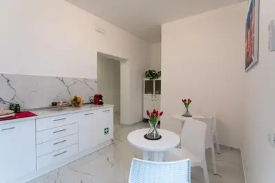 a kitchen with white cabinets and a table and chairs at Re di Roma Rooftop in Rome