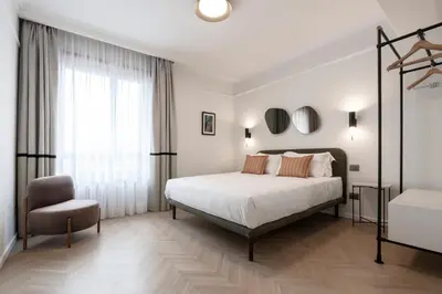 a white bedroom with a bed and a chair at Be Mate Colosseo in Rome