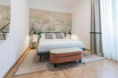 a bedroom with a large bed and a ottoman at Be Mate Trastevere I in Rome