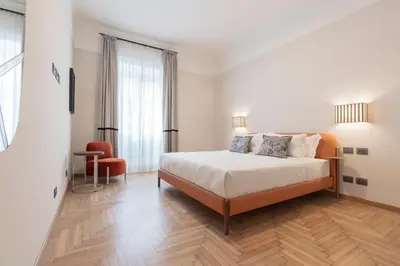 a white bedroom with a bed and a chair at Be Mate Trastevere I in Rome