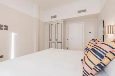 a white bedroom with a bed with striped pillows at Be Mate Trastevere II in Rome