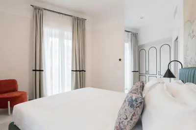 a white bedroom with a bed and a chair at Be Mate Trastevere III in Rome