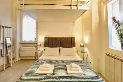 a bedroom with a large bed with two white chairs at Cozy Studio Flat in Trastevere by Yourhost in Rome