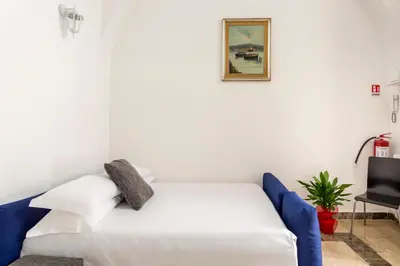 a bedroom with a white bed and a blue chair at Sanniti' Home in Rome