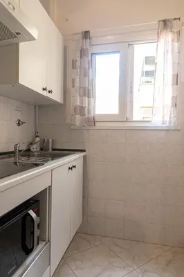 a white kitchen with a sink and a window at Vatican Walls Apartment in Rome
