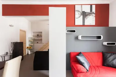 a living room with a red couch and red accent wall at Attic Vatican Flat - San Pietro in Rome