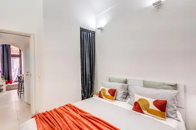 a white bedroom with a bed with colorful pillows at Studio Artis Piazza di Spagna in Rome